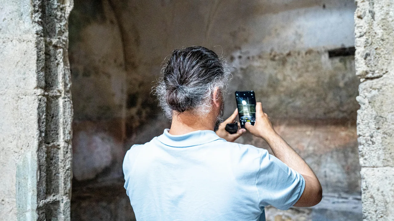 Person photographing damp patch on wall with smartphone, documentation