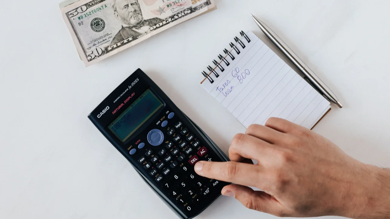 Calculator and notepad with pricing breakdown on desk